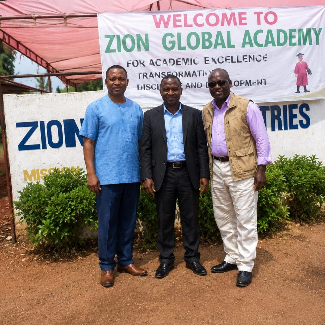 Smiling men in front of academy sign.