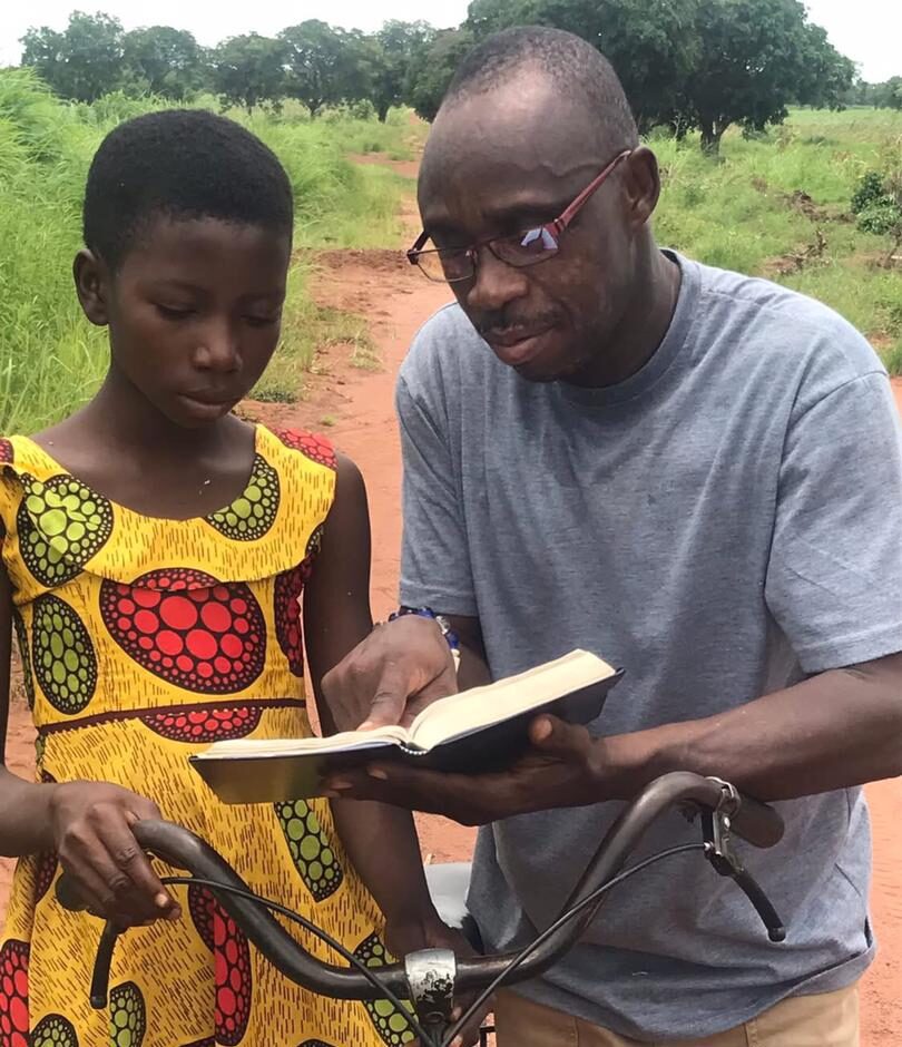 Man reading book with girl beside bicycle