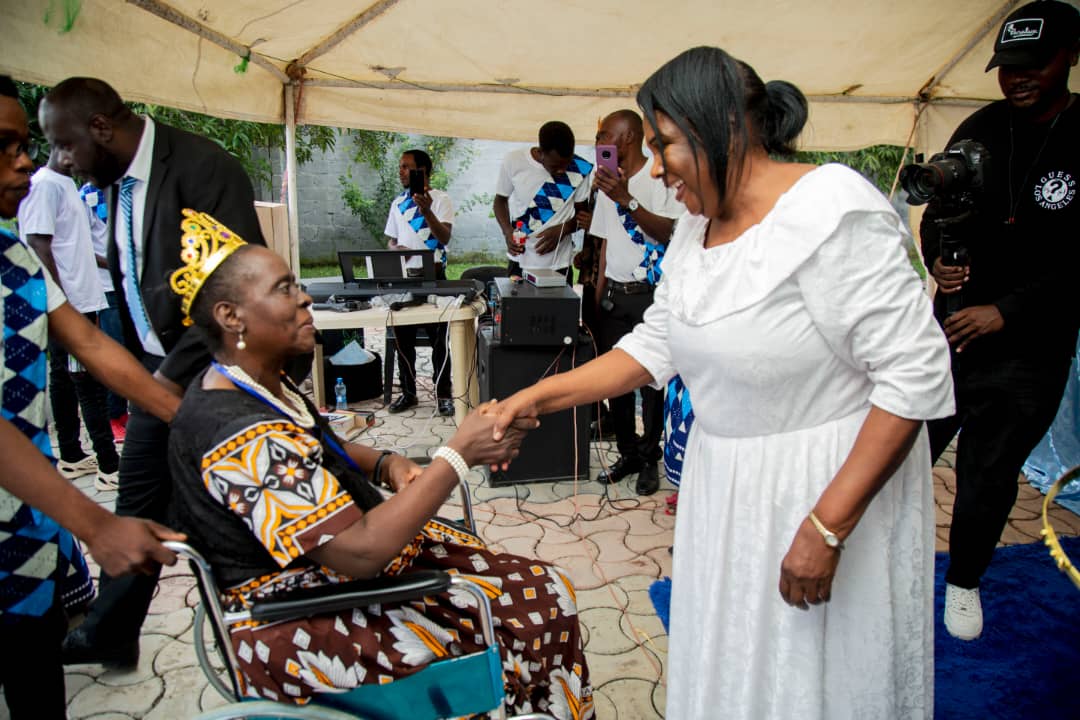Woman in white shaking hands with crowned elder
